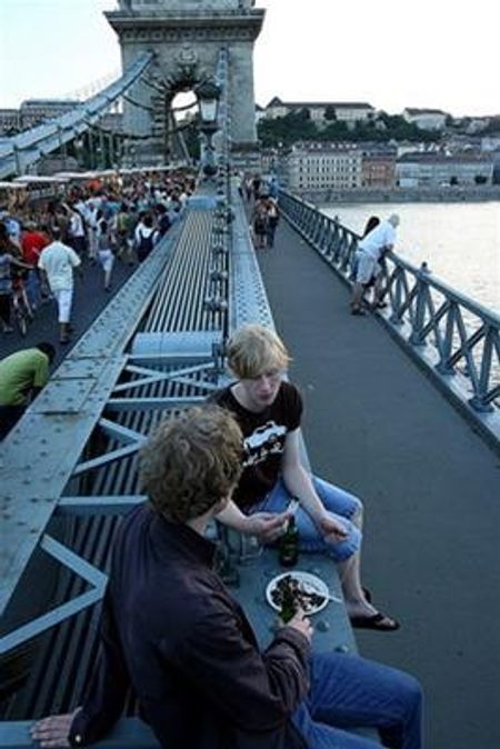Và uống vì ánh hoàng hôn màu tím với hai anh bạn trẻ đang ngồi trên dải dây văng của cầu