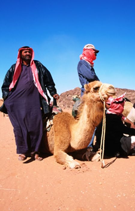 Hai người đàn ông Ả Rập du cư chuẩn bị cưỡi lạc đà băng qua vùng sa mạc Wadi Rum.